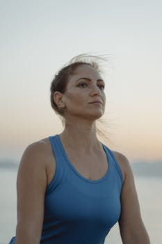 A serene portrait of a woman in a blue tank top during sunset, reflecting calmness and inner peace.