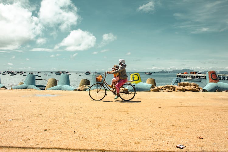 Woman Riding A Bicycle With A Baby On The Beach 