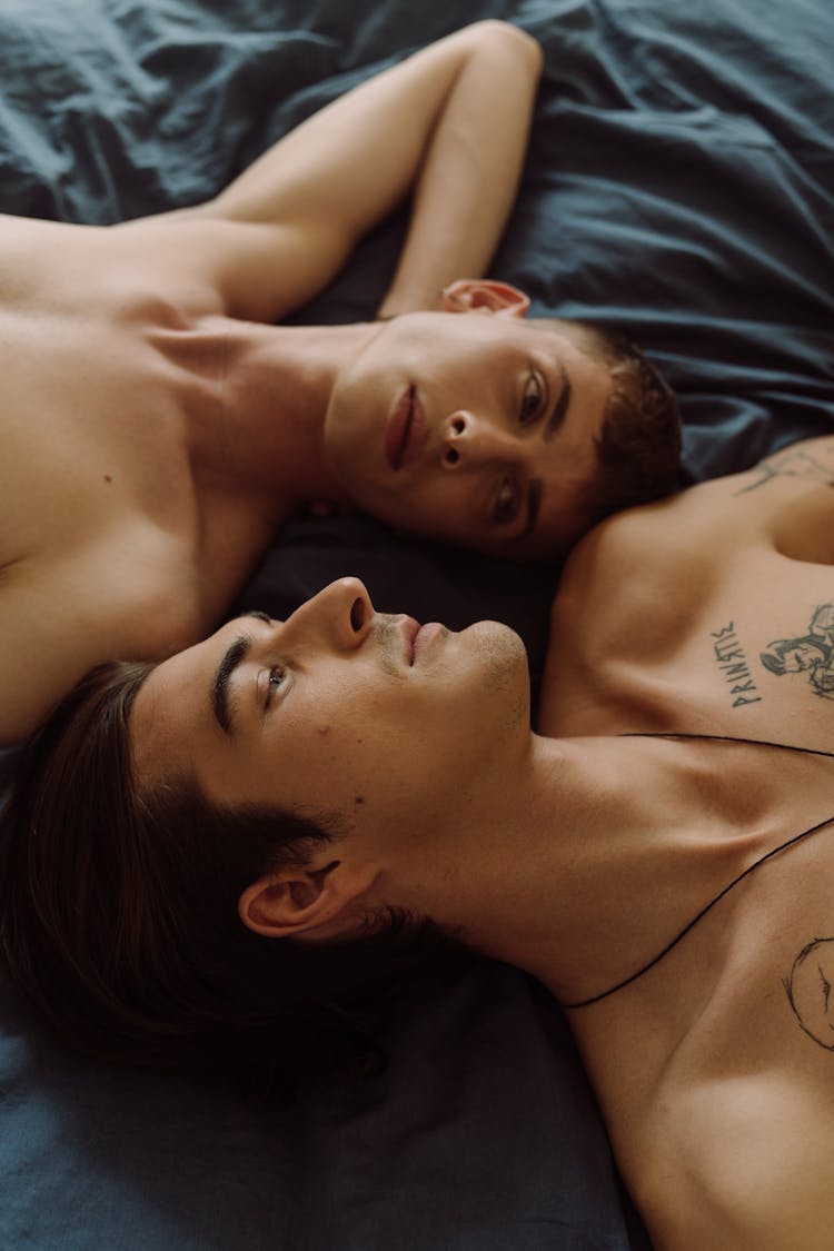 Topless Men Lying On Bed