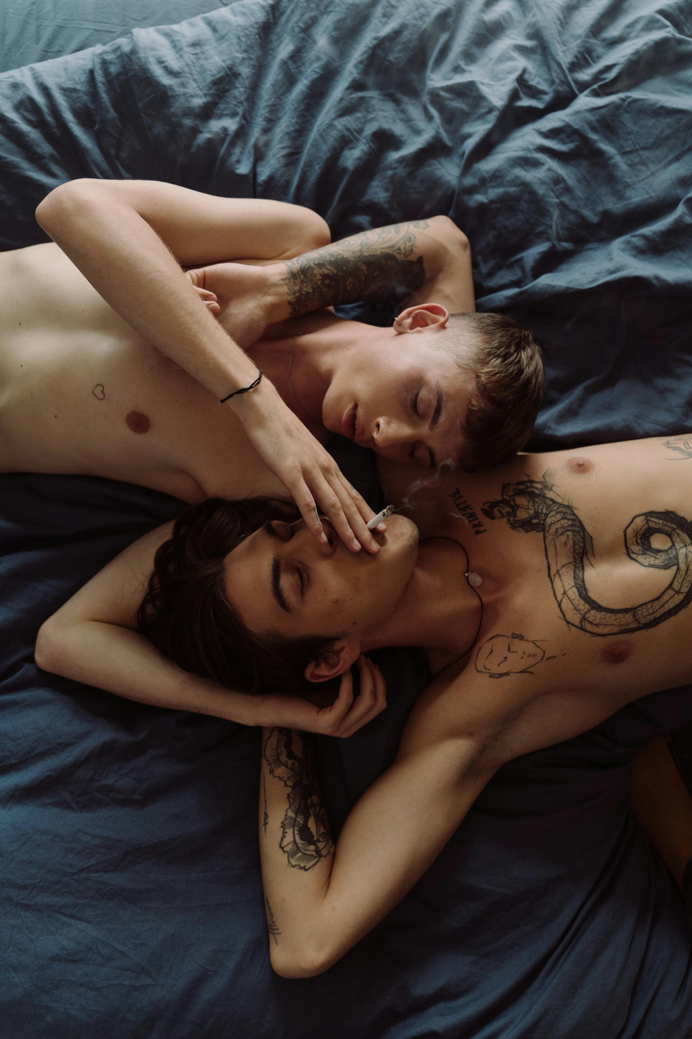 topless man lying on bed beside woman