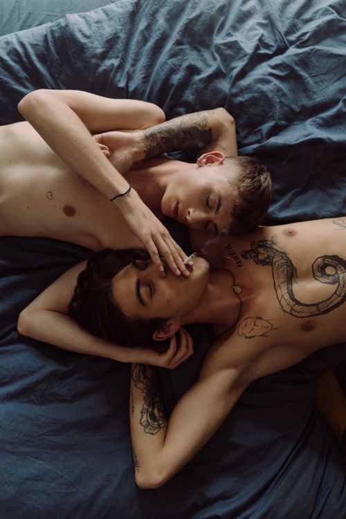 Free Two tattooed men sharing a moment of intimacy and relaxation in a cozy bedroom setting. Stock Photo