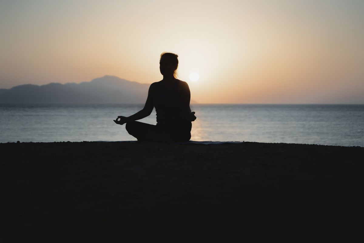 Woman practicing yoga at sunset on the beach