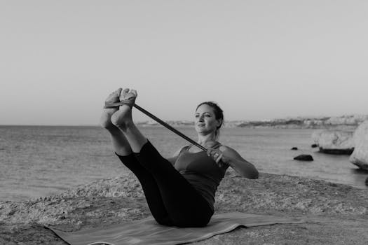Woman performing yoga at the coast during sunset, promoting health and mindfulness.