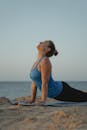 白天在海边的垫子上表演瑜伽姿势的白人妇女