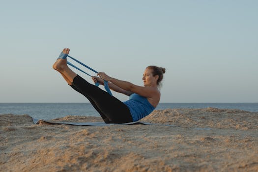 A woman performs yoga stretches on a mat near the sea during sunset, embodying relaxation and fitness.