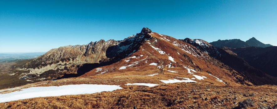 Captivating mountain landscape with snow patches under a clear blue sky, perfect for nature lovers.