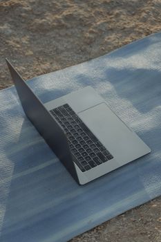 A sleek laptop rests on a yoga mat outside, blending work with relaxation.