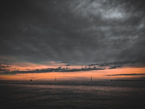 Body of Water Under Cloudy Sky during Sunset