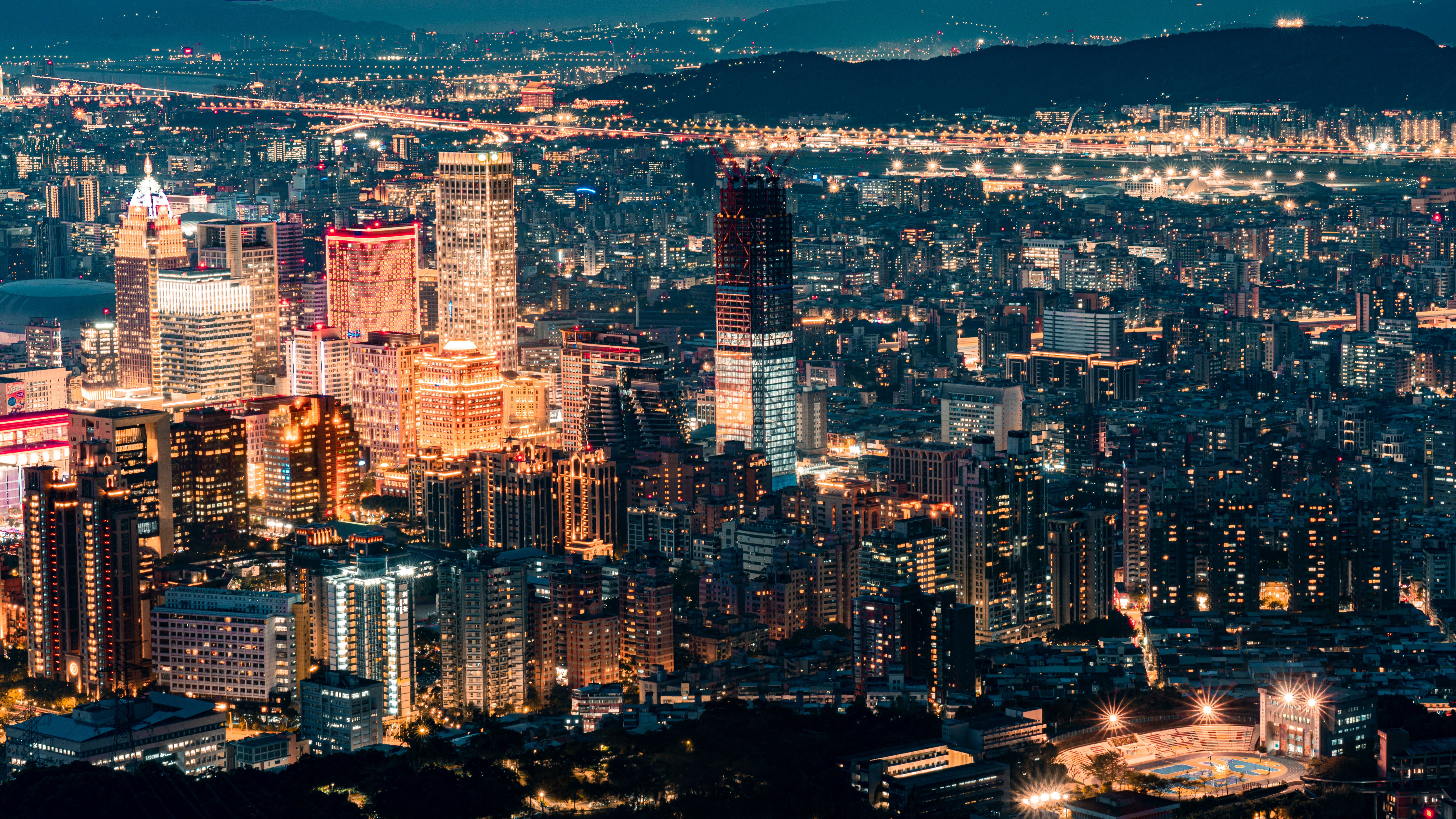 现代城镇的鸟瞰图中，夜间道路附近可见发光的建筑物和摩天大楼