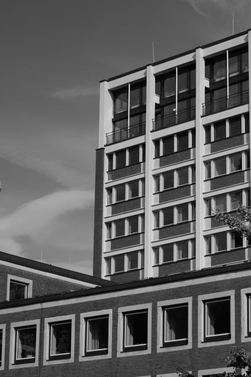 Free Black and white photo of a modern urban building with glass windows and concrete structure. Stock Photo