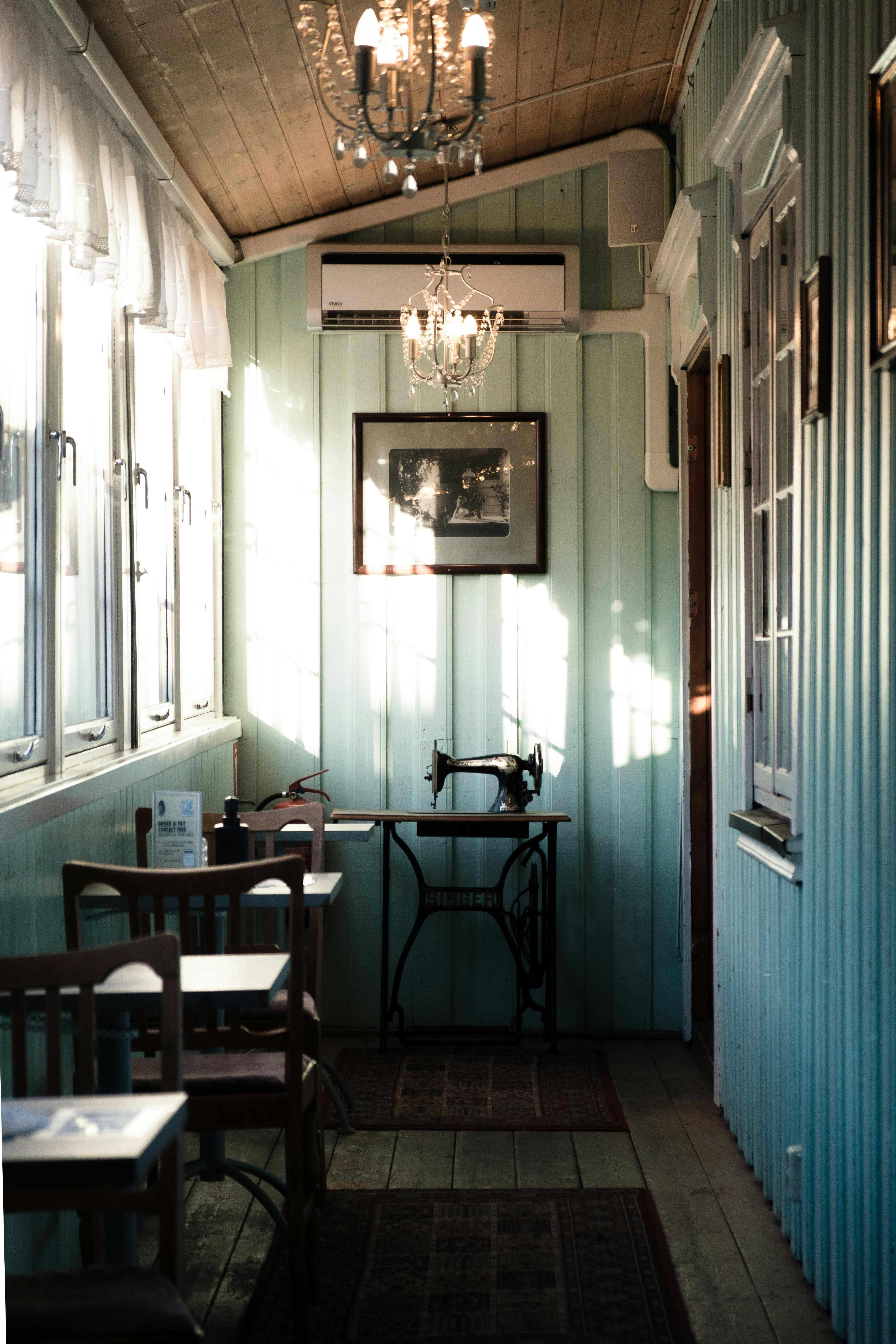 Charming vintage sewing machine set in a sunlit room with teal paneling and elegant chandelier.