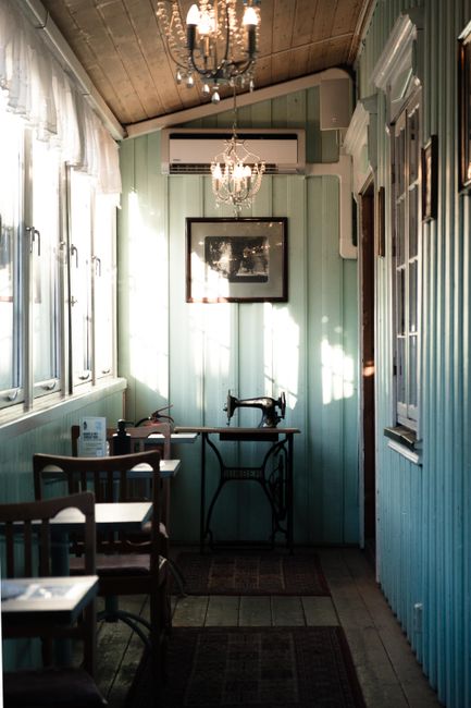 Charming vintage sewing machine set in a sunlit room with teal paneling and elegant chandelier.
