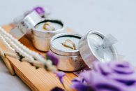 Golden wedding rings in small grey boxes on wooden stand with purple flowers