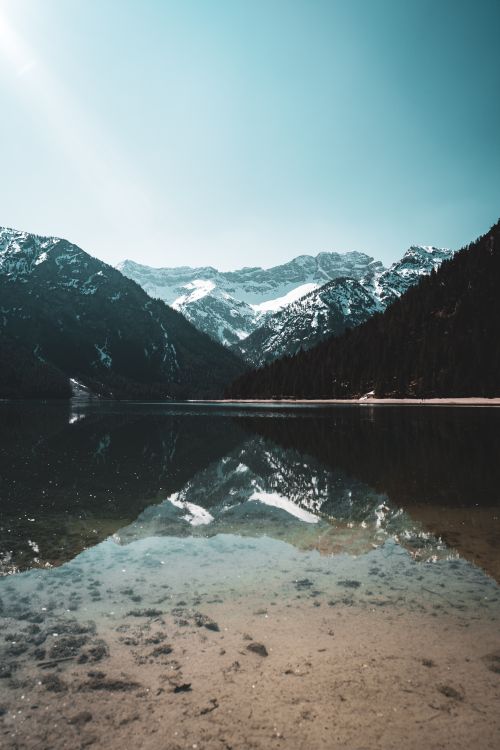 Free Stunning reflection of snow-covered Alps in a serene lake in Tirol, Austria, creating a mesmerizing natural landscape. Stock Photo