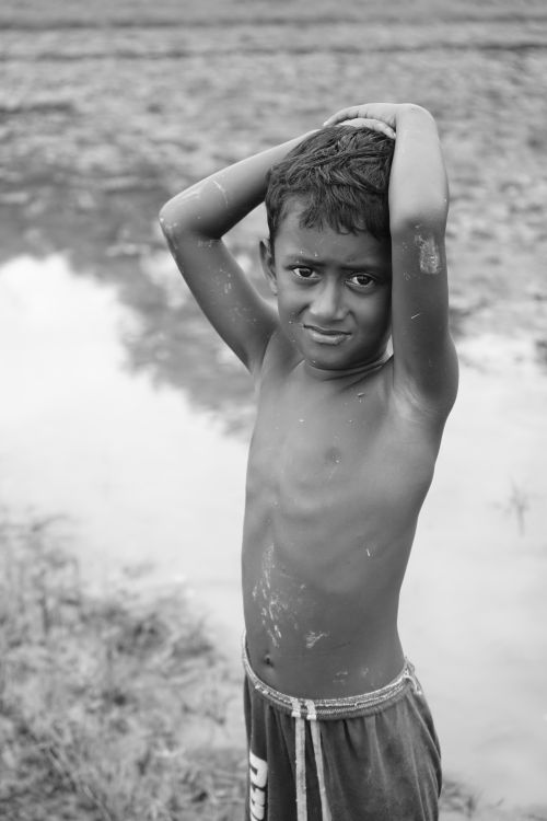Free Black and white portrait of a young boy standing outdoors in rural Bangladesh. Stock Photo