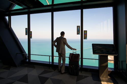 Free Man Standing with a Luggage and Looking at the View of an Ocean  Stock Photo