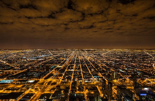 A breathtaking aerial view of Chicago at night, showcasing vivid city lights and a dramatic sky.