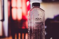 Detailed view of an Aqua Carpatica water bottle with droplets and blurred background.