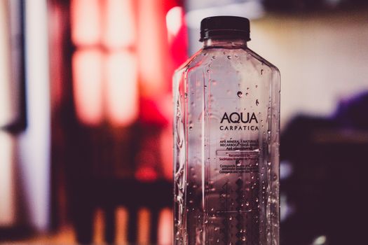 Detailed view of an Aqua Carpatica water bottle with droplets and blurred background.