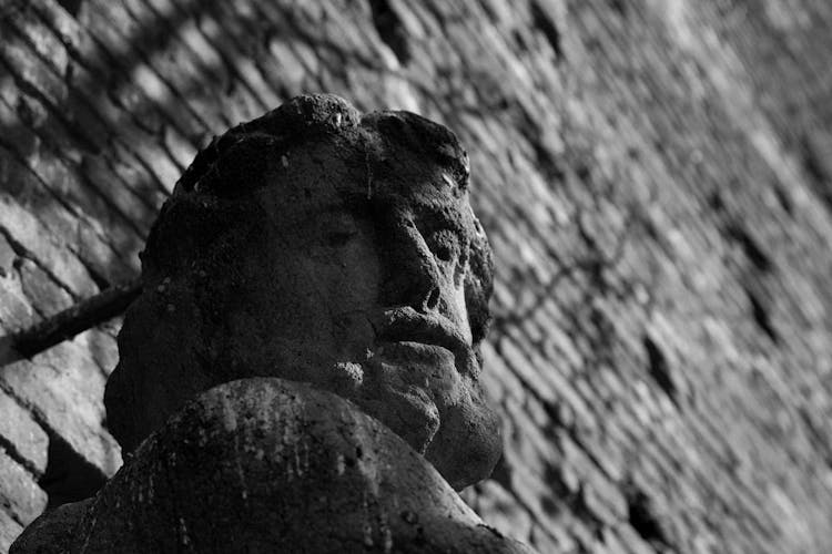 Shabby Old Statue Near Brick Wall In Street