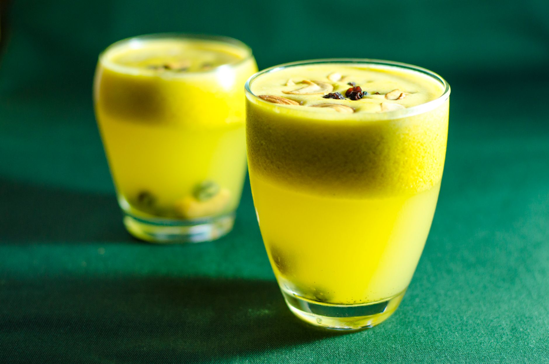Glass jars of turmeric immunity drink with lemon wedges and black pepper
