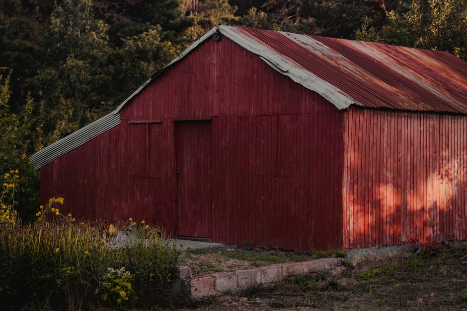 A rustic red barn surrounded by lush countryside, capturing a serene rural atmosphere.