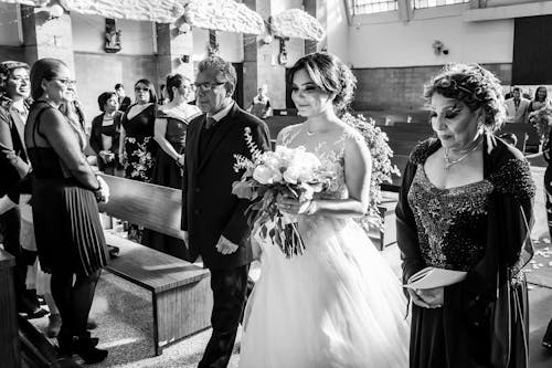 Grayscale Photo of People Walking Down the Aisle