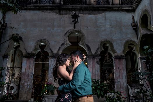 一对夫妇在一座建筑独特、郁郁葱葱的古老庭院里，分享了亲密的时刻