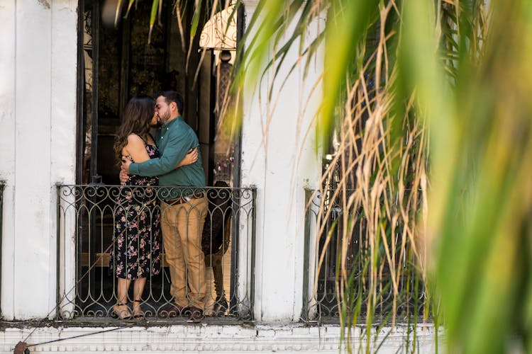 A Couple Kissing On A Balcony 