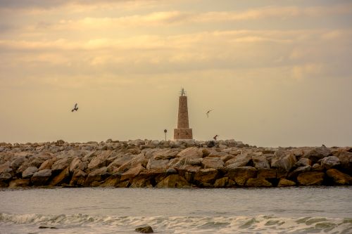 Free Dramatic view of a lighthouse on the rocky Marbella coast, Spain, at dawn. Stock Photo