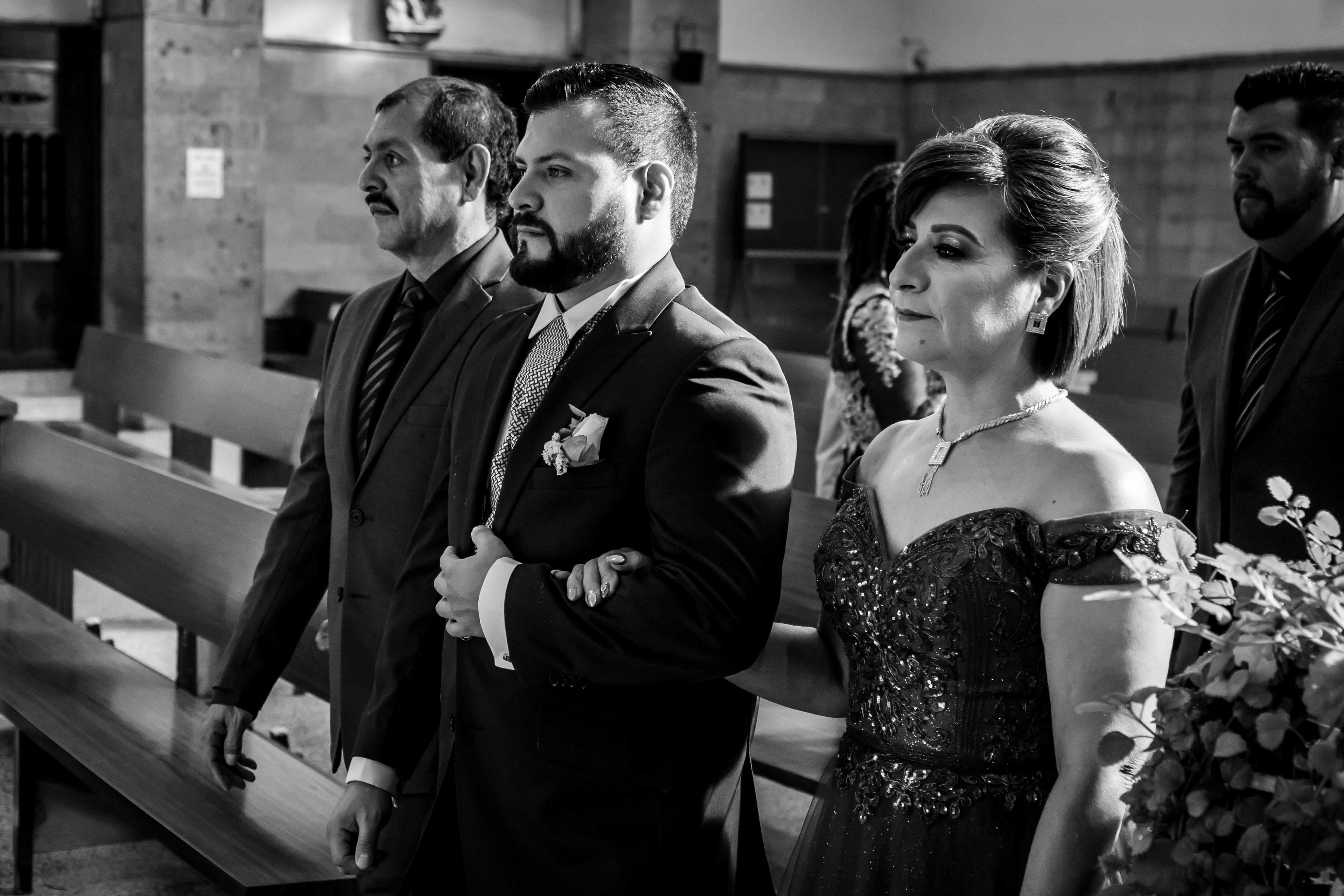 mother of the groom holding a small notecard at a podium during wedding reception, guests attentively watching, warm venue lighting