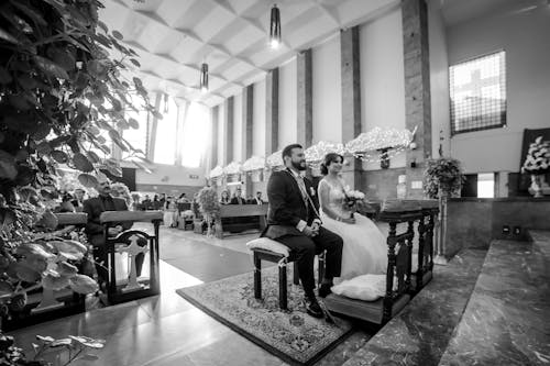 Grayscale Photo of Man and Woman Sitting in Front of an Altar