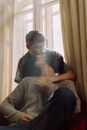 Man Kissing His Partner's Forehead while Sitting by the Window