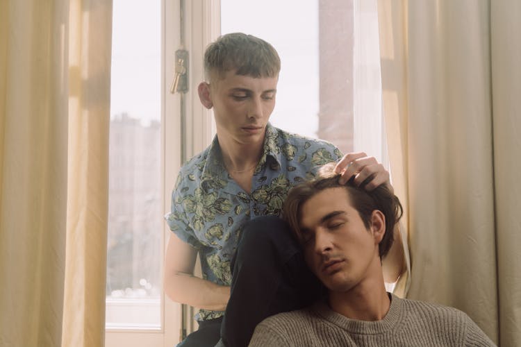 Couple Running Fingers Through Hair While Sitting By The Window