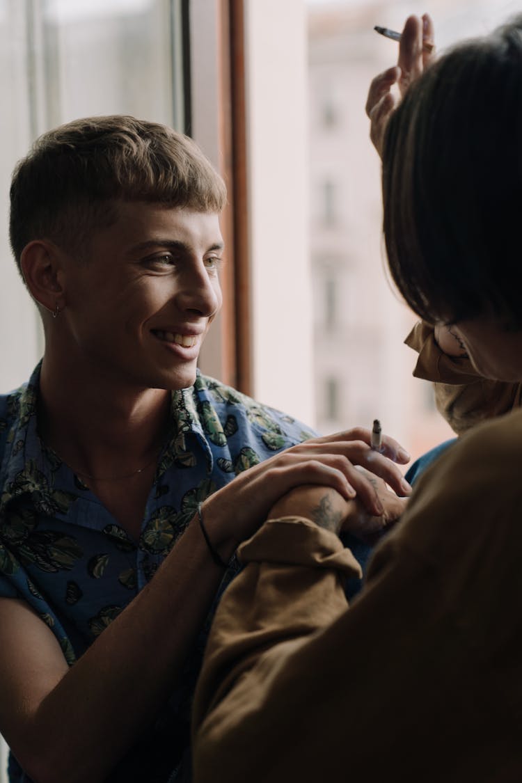  Couple Sitting By The Window Holding Hands While Smoking Cigarettes