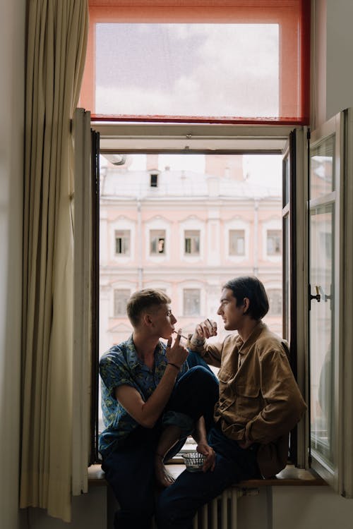 Free People Sitting at the Window Sill Smoking Stock Photo