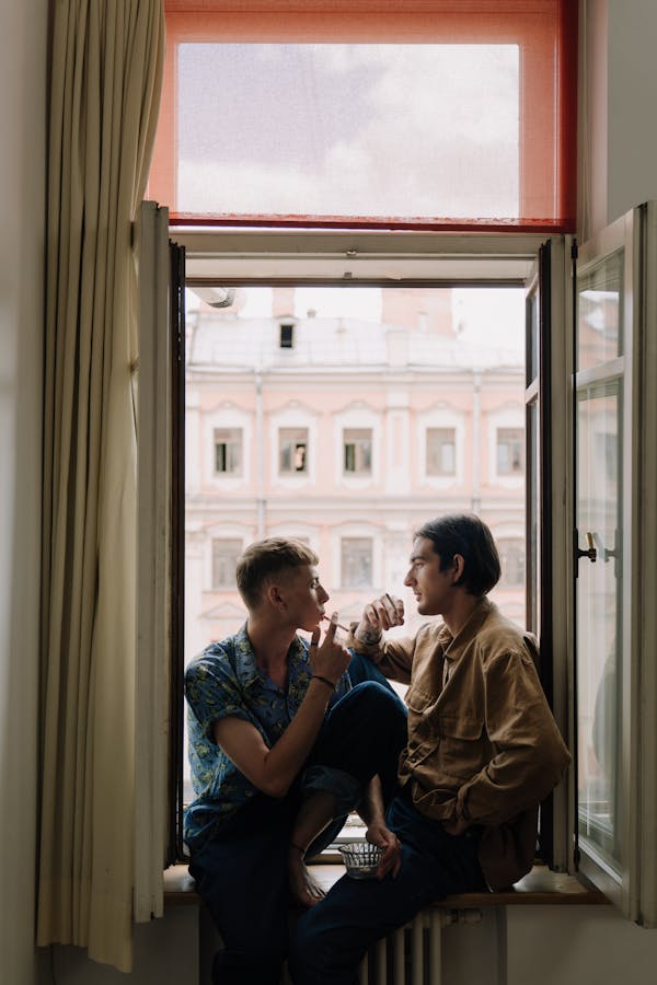 People Sitting at the Window Sill Smoking