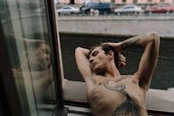 Topless Man with Tattoo Lying on Window Sill
