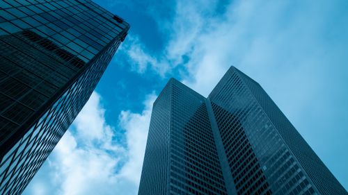 Free A dramatic low angle shot of modern skyscrapers against a vibrant blue sky. Stock Photo