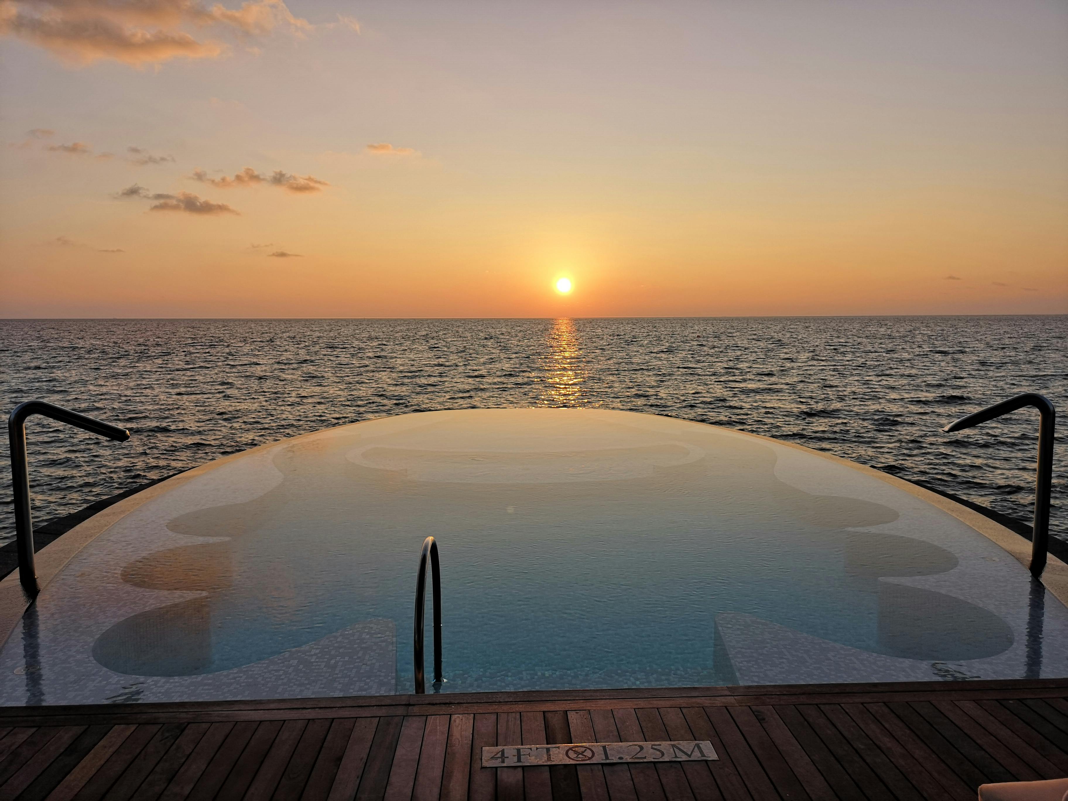 swimming pool with view of the seacoast at sunset