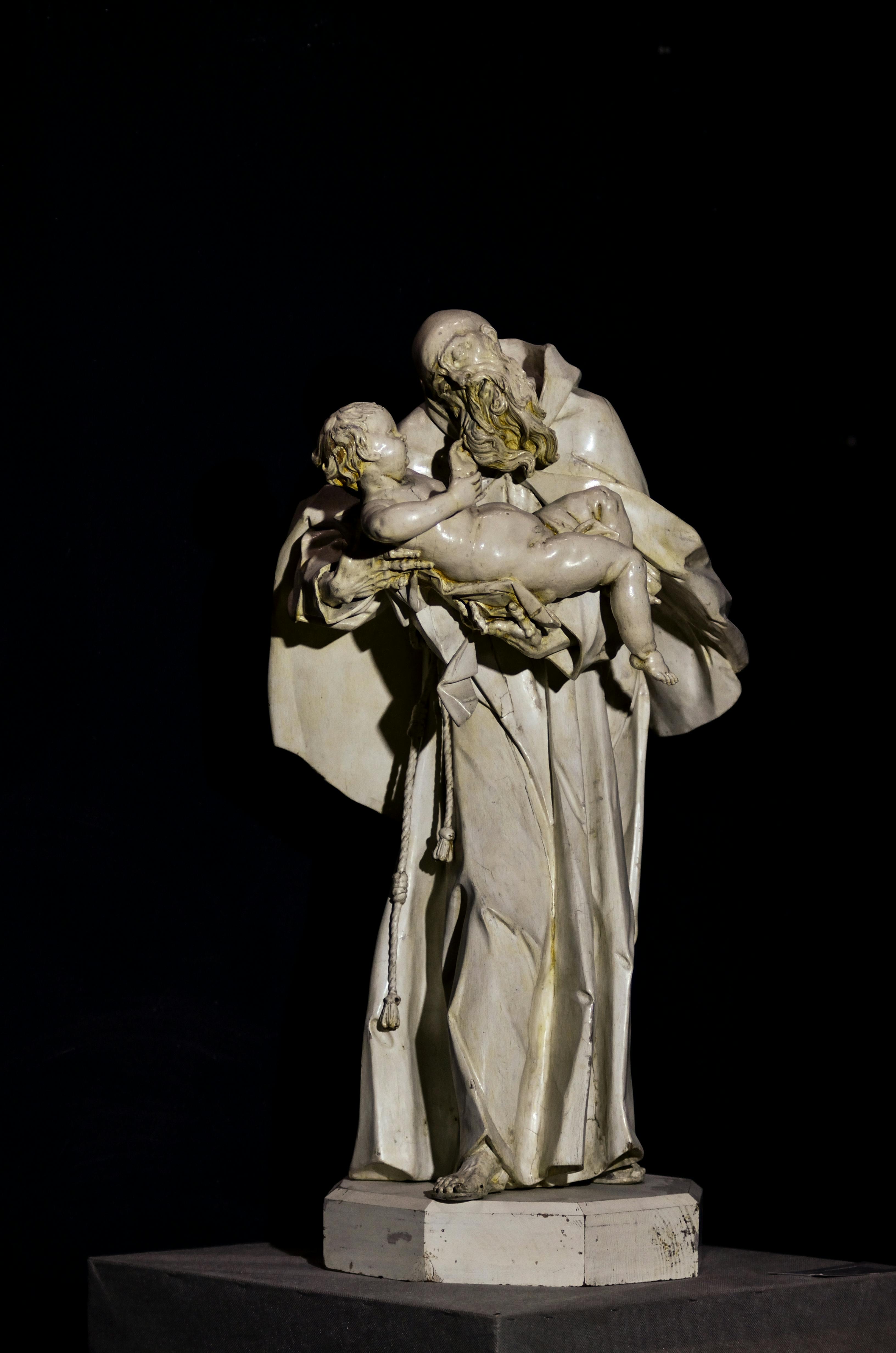 Detailed view of a renaissance style marble statue against a black background.