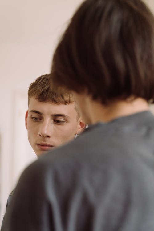 Sad Looking Young Man Standing next to a Person Facing Away from the Camera