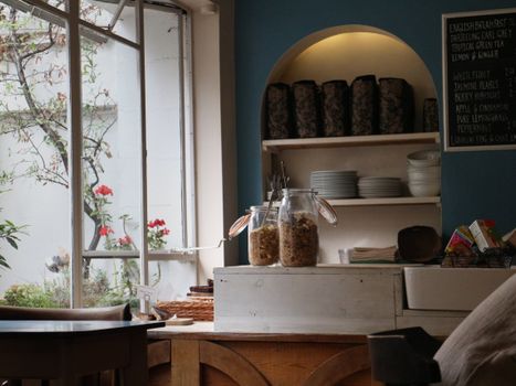 Charming London café interior featuring jars of granola and a view of the garden, with natural light streaming through large windows.