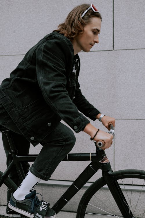 黑色外套和黑色的褲子，騎在黑色自行車上的人