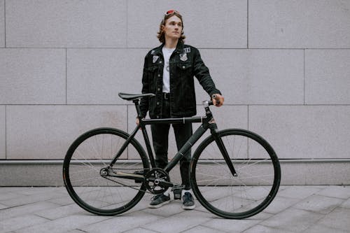 黑色外套和黑色的褲子，站在黑色自行車旁邊的女人