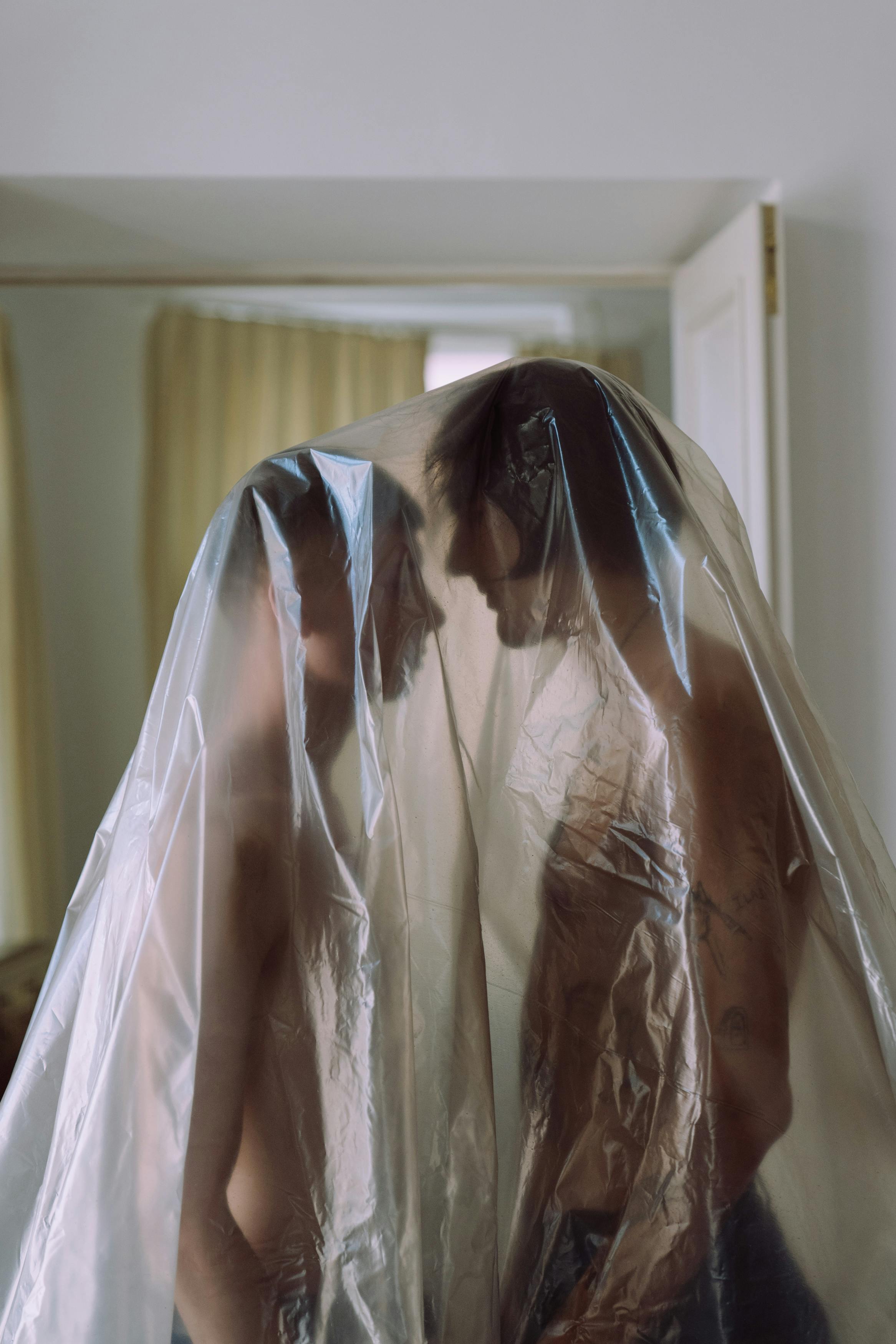 Two men sharing an intimate moment under cellophane indoors.