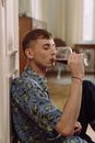 Man in Blue and White Floral Shirt Drinking from Clear Drinking Glass
