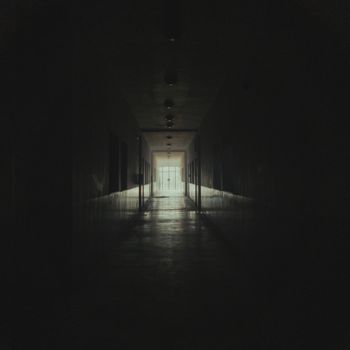Moody and atmospheric dark corridor leading to a lighted doorway.