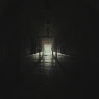 Dark corridor leading to a lit doorway — photo by Amine Mayoufi on Pexels
