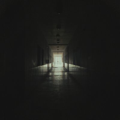 Dark corridor leading to a lit doorway — photo by Amine Mayoufi on Pexels